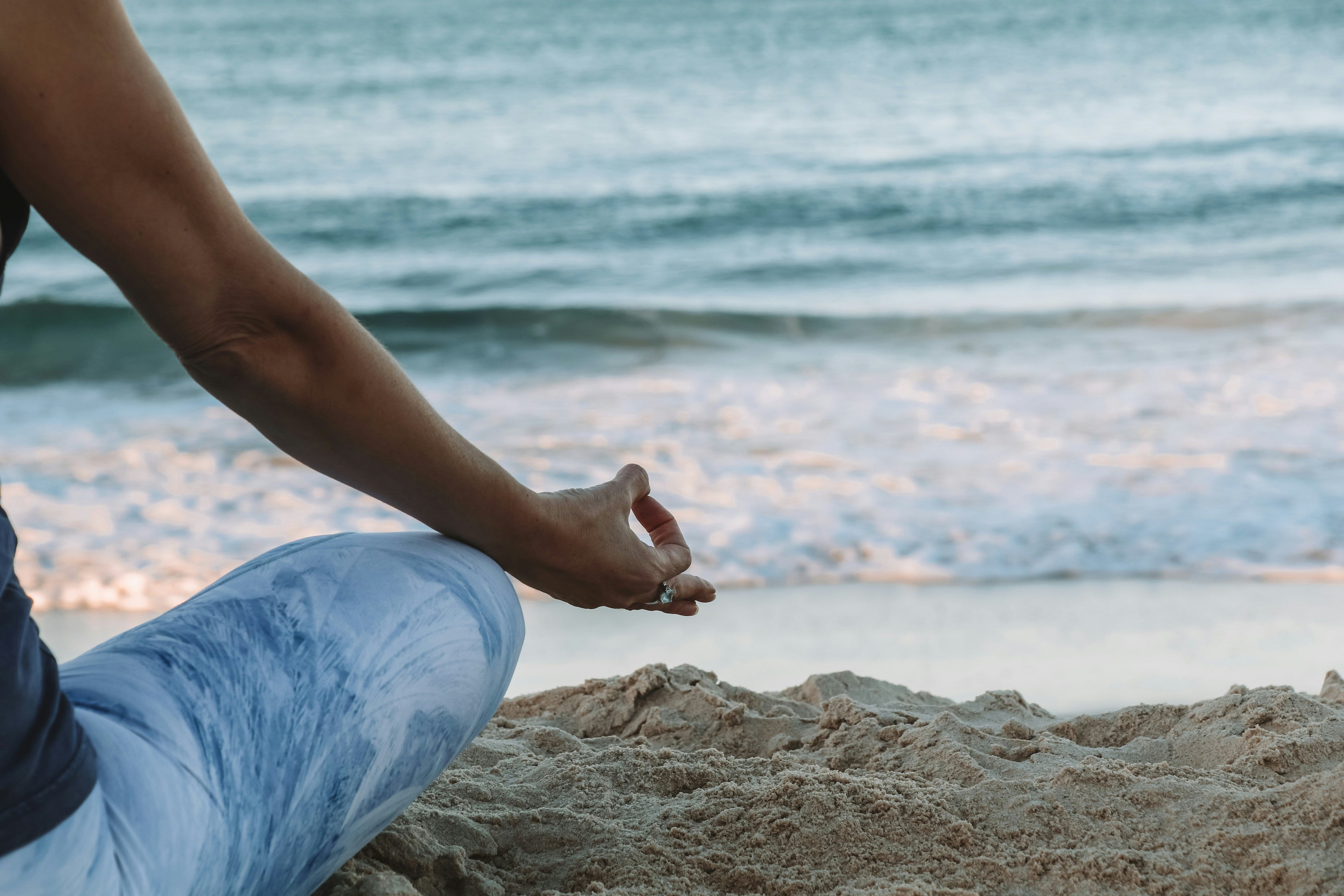 Woman mediating on the sand overlooking ocean. Picture is linked to blog post about mediations